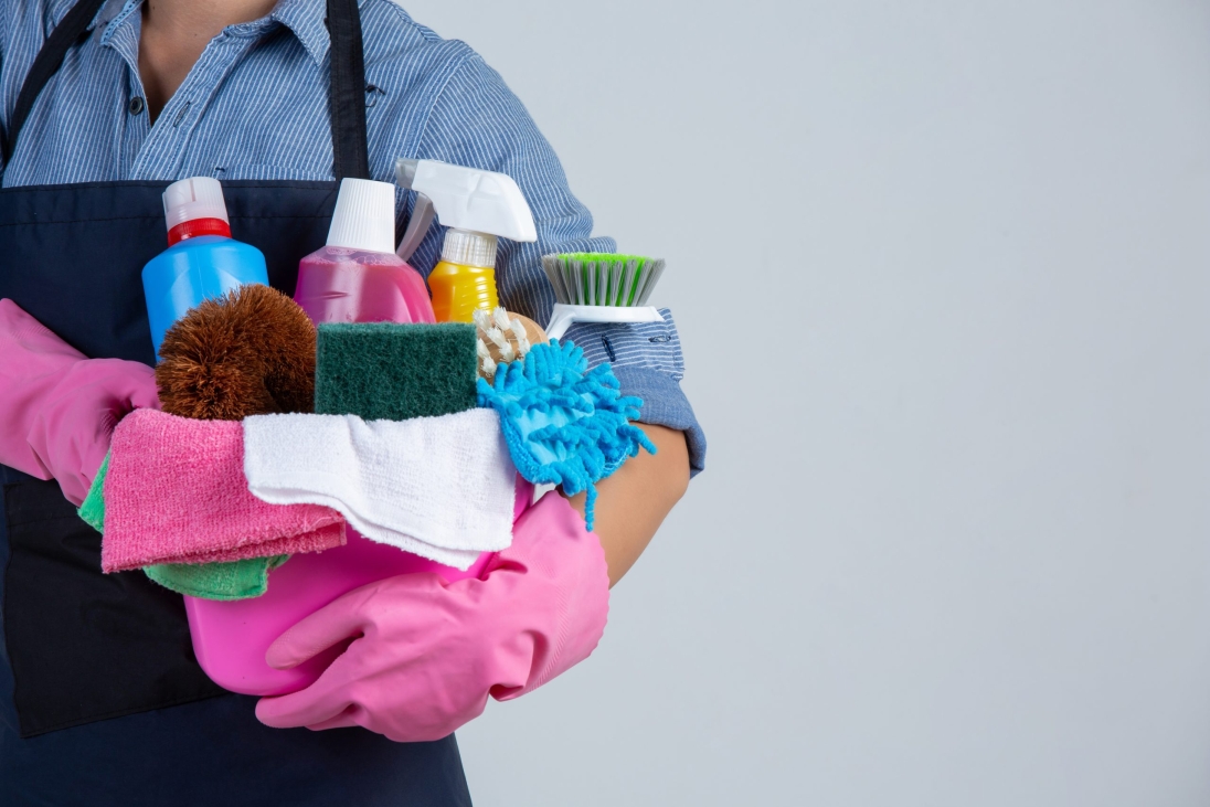 young-girl-is-holding-cleaning-product-gloves-and-rags-in-the-basin-on-white-wall
